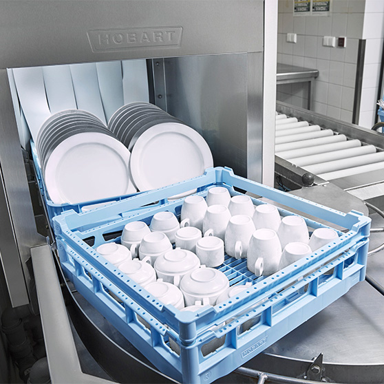 Racks of clean white plates and cups at the opening of a Hobart commercial dishmachine